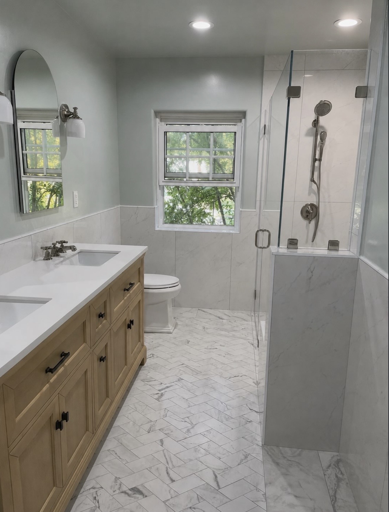 Herringbone marble floor with wood vanity and glass shower